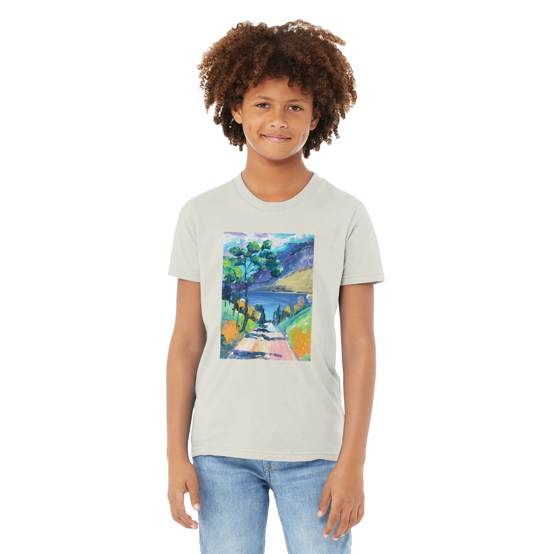 Boy wearing a t-shirt with a colourful landscape design on a white background
